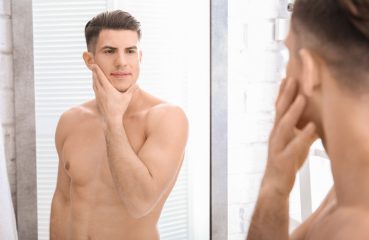 Blond Man Considers Face in Mirror