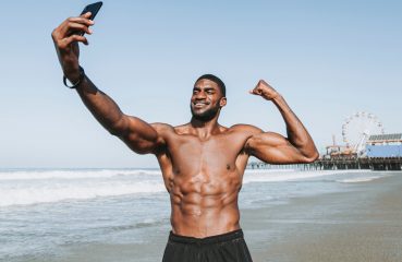 A Fit Man on a Beach Taking a Selfie