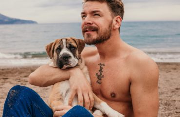 Shirtless man with dog on the beach